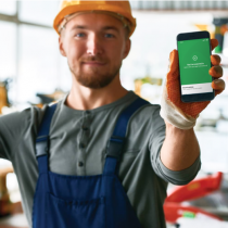 A tradesperson holding a phone which shows that they have signed in